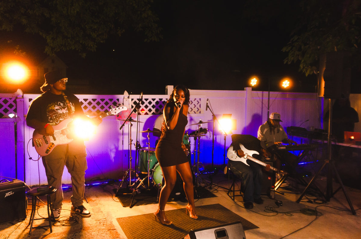 A singer performing with a live band at DMV Backyard Jam.