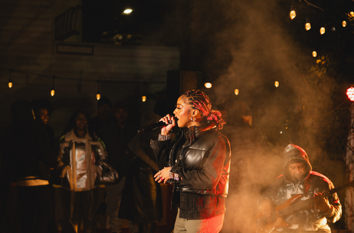 Singer performing under the string lights at DMV Backyard Jam